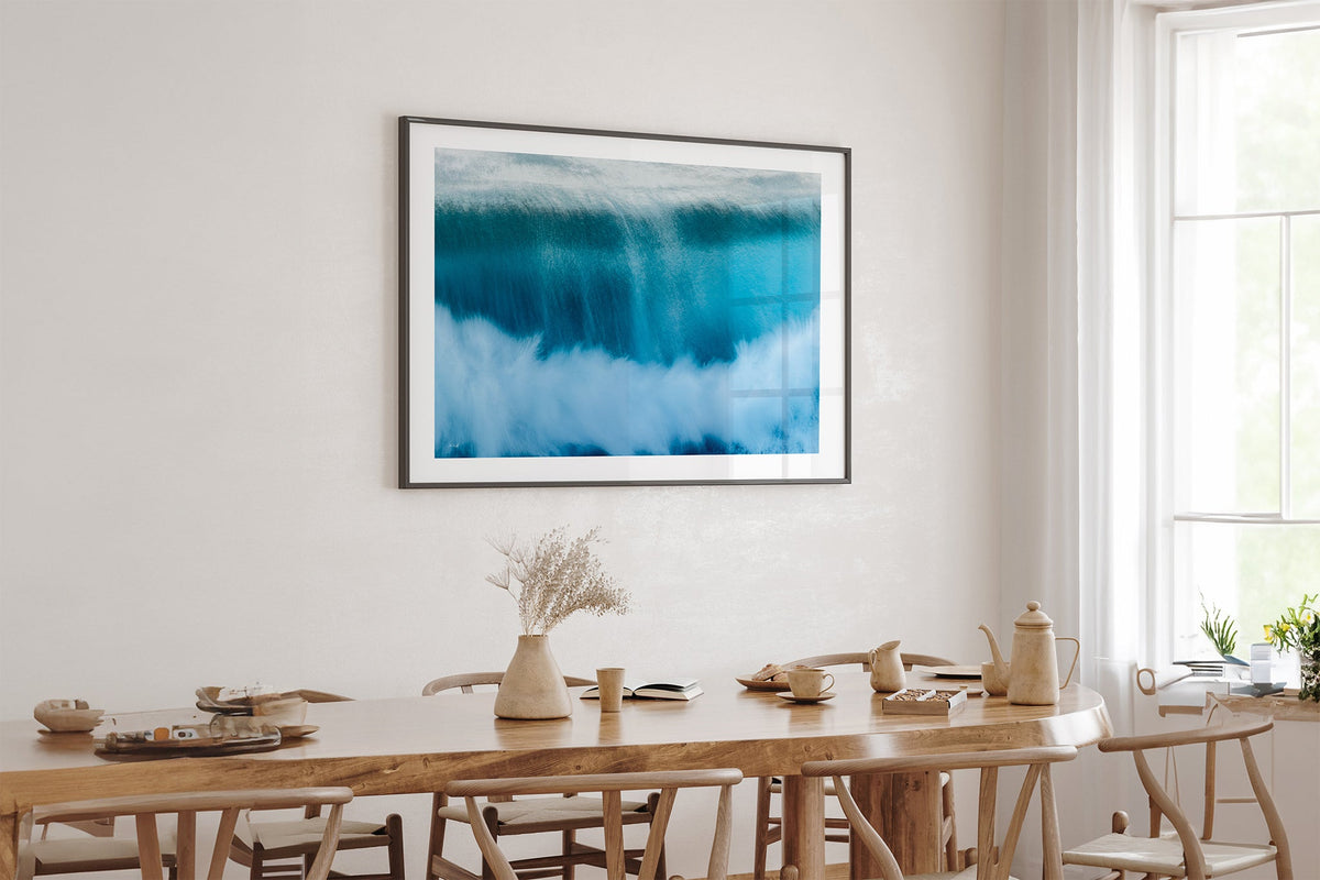 Deep Impact wave print shown framed in black above an oak table.