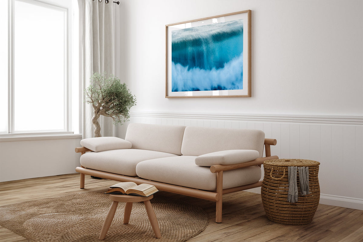 Deep Impact wave print shown framed in oak above a linen couch.