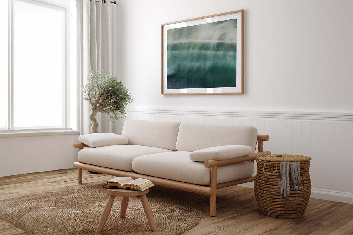 Glistening Spray wave print shown framed in oak above a linen couch.