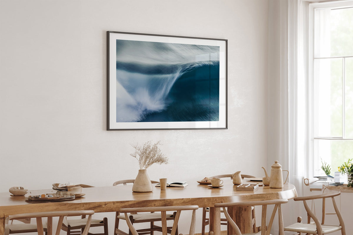 Impact Blur wave print shown framed in black above an oak table.