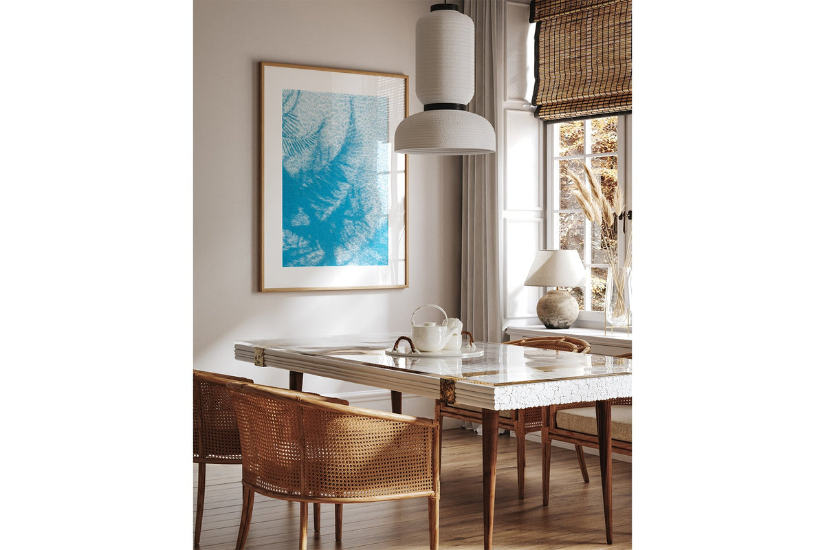 Pool Palms print shown framed in oak above a dining table.