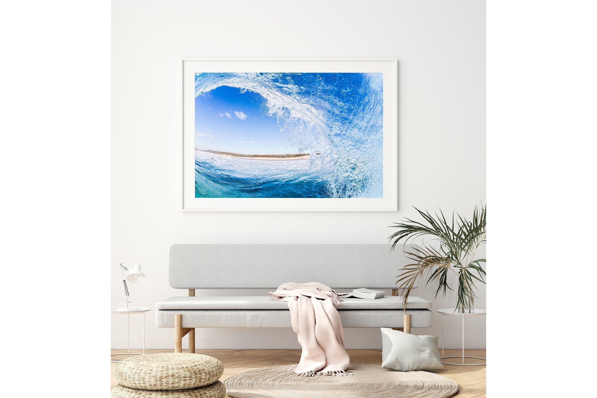 Blue barrel wave print shown framed in white, hung above a grey bench seat in a neutral toned living room.