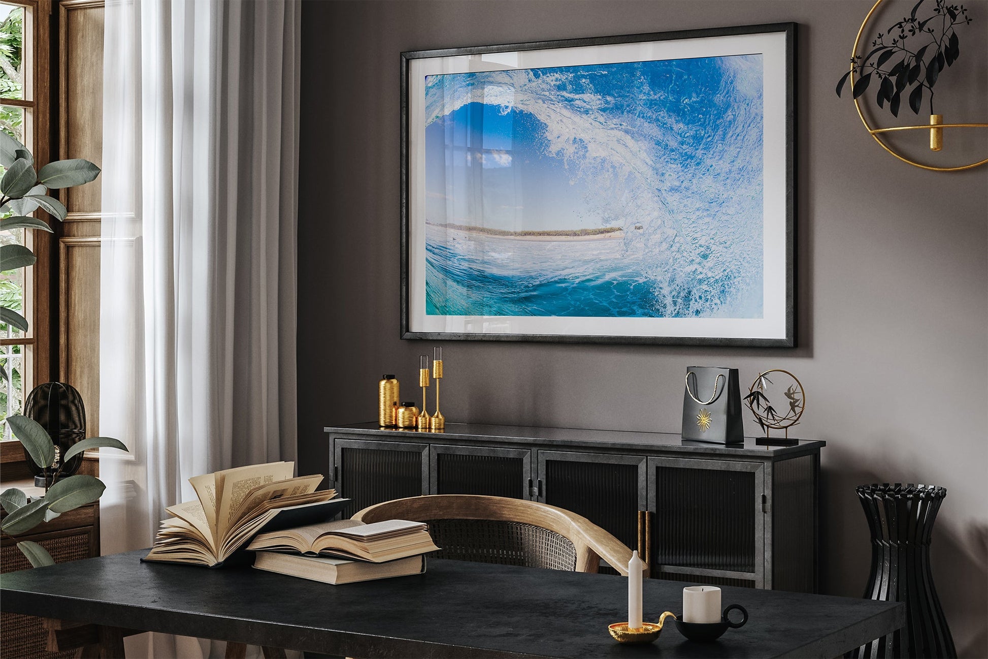 Blue barrel wave print shown framed in black, hung in a moody dark toned study with gold accent decor.