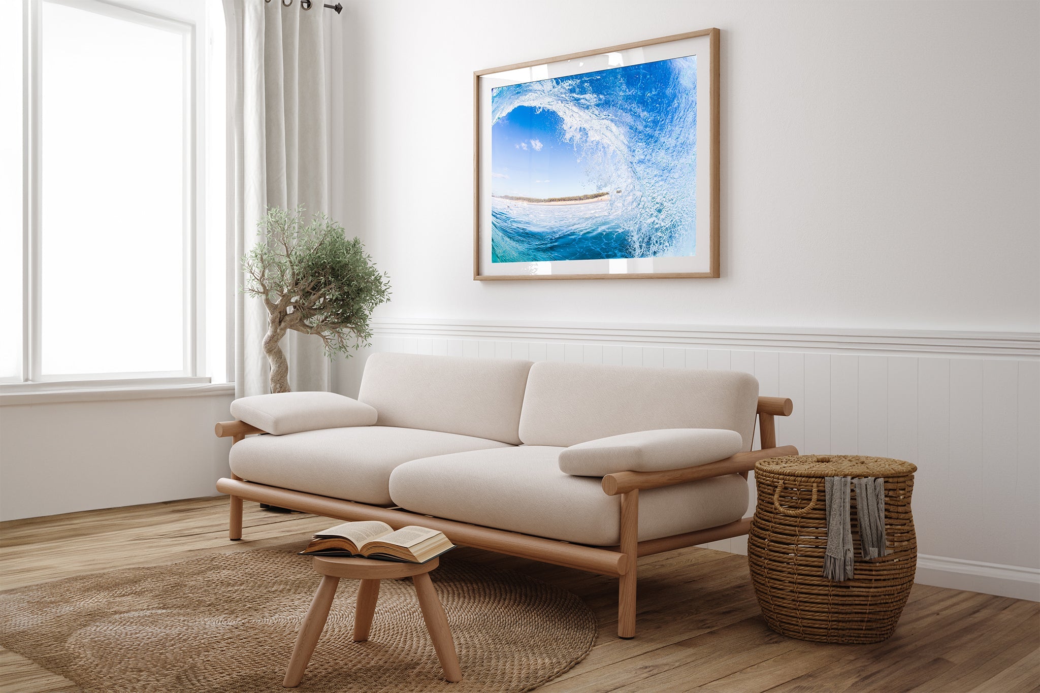 Blue barrel wave print shown framed in oak, hung above a cream sofa in a light, plant filled living room.