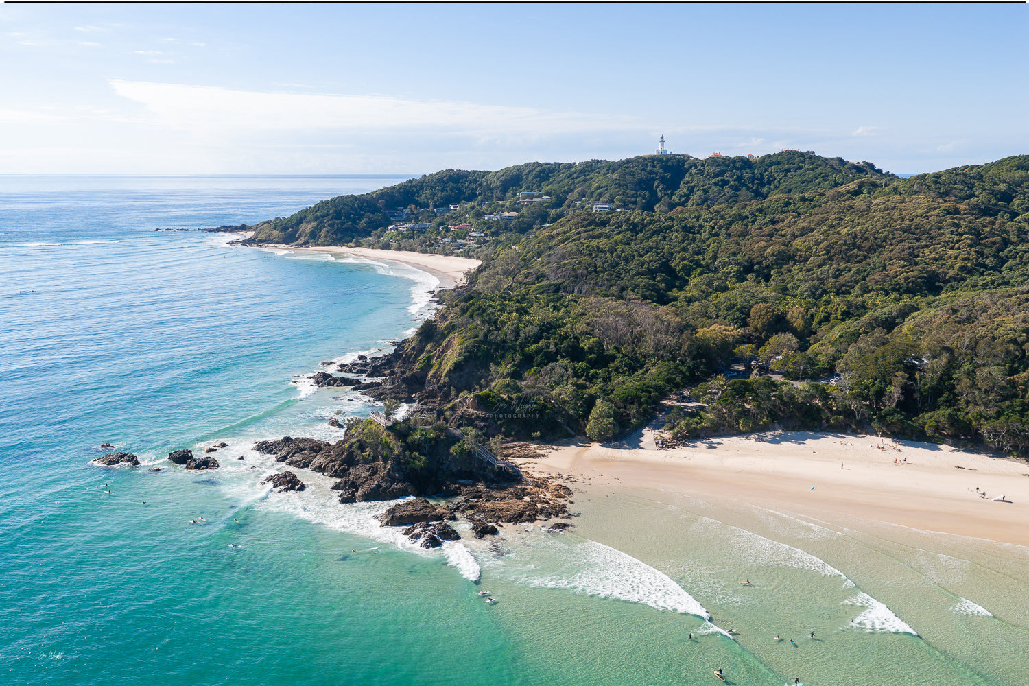 Aerial view of The Pass, Byron Bay, turquoise water and surfers, Cape Byron lighthouse on the headland, an aerial wall print.