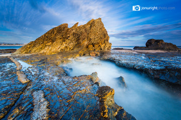 Long-exposure fine art photograph at Currumbin, QLD, golden lit jagged rocks with mist-like smoothed water flowing through rock pools.