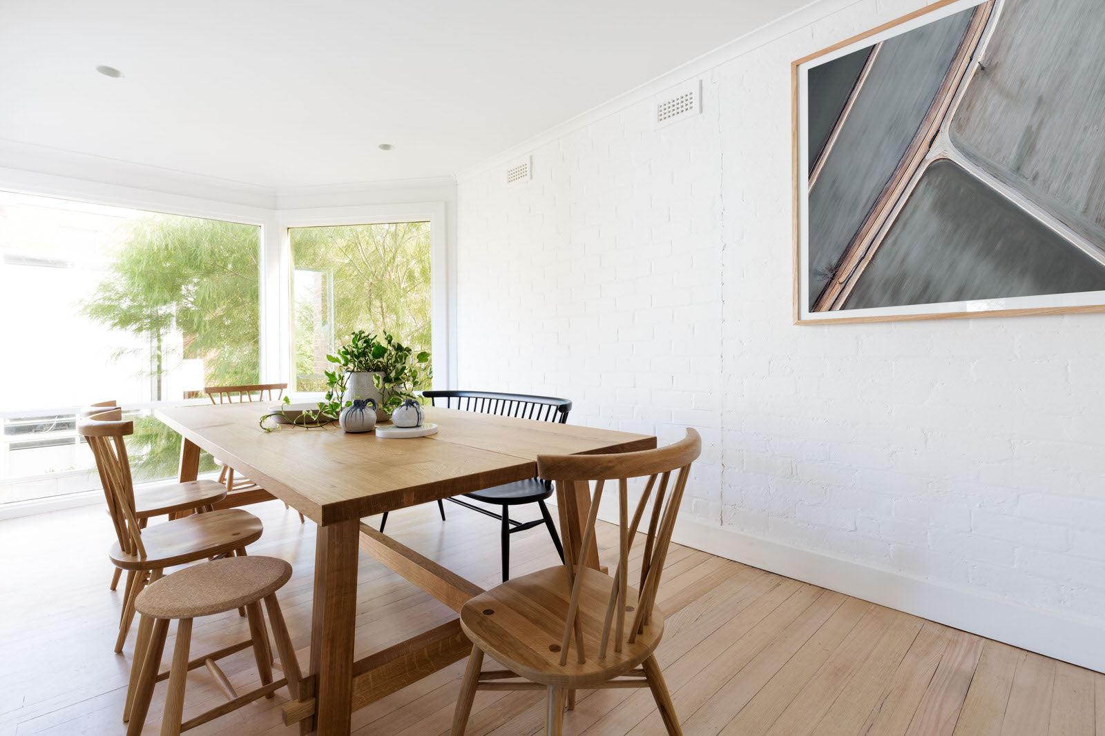 clean white interior with oak wooden table and abstract earth art