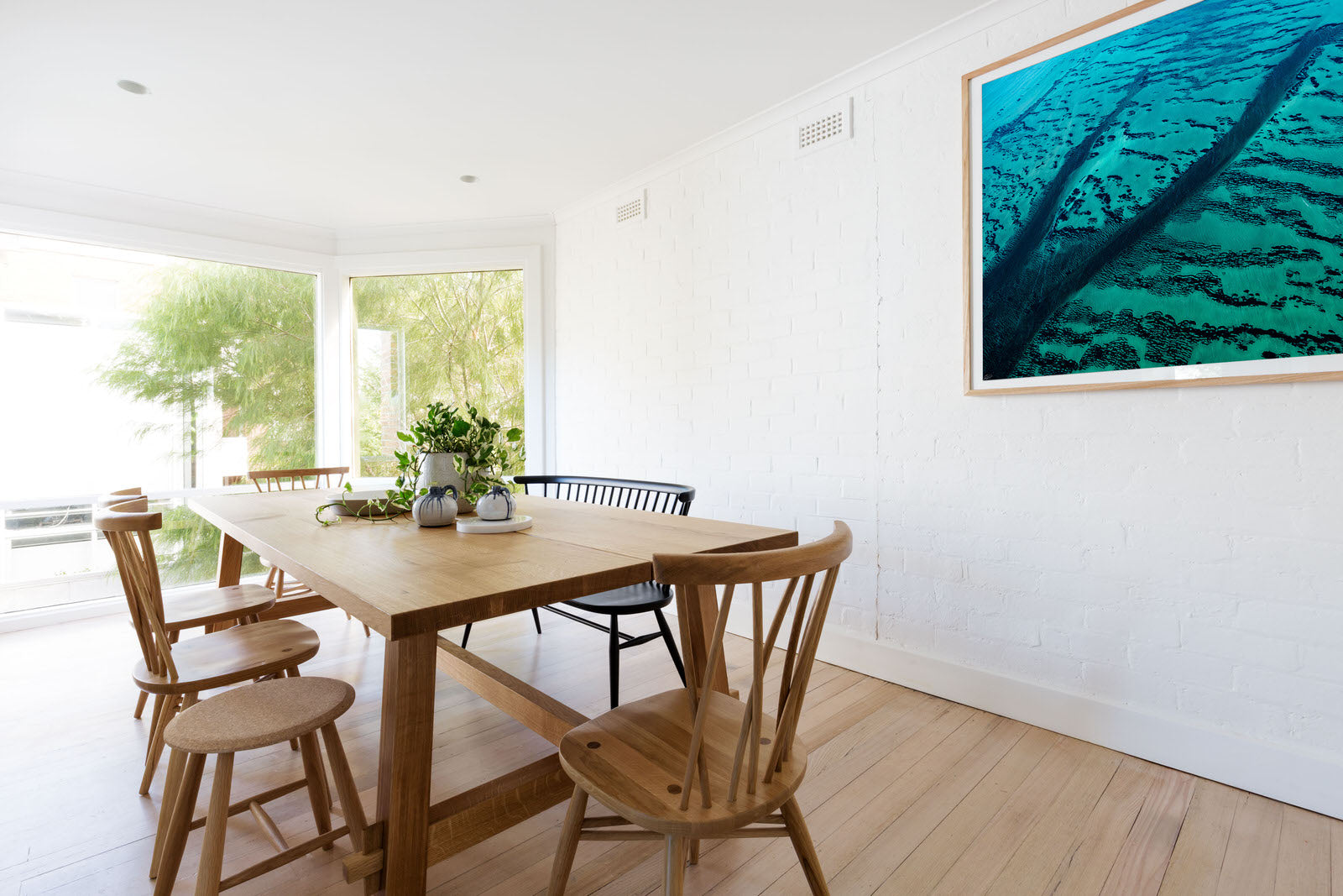 Clean white interior with oak floor and table hanging oak abstract art