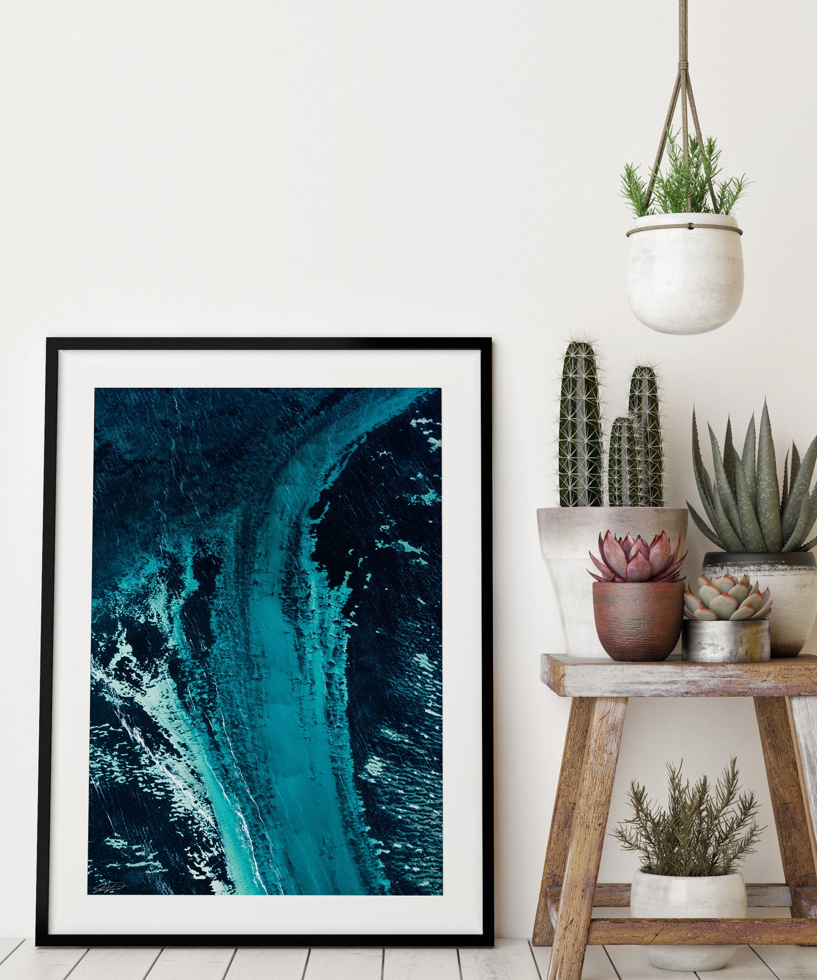 black frame with blue art against a wall with cactus